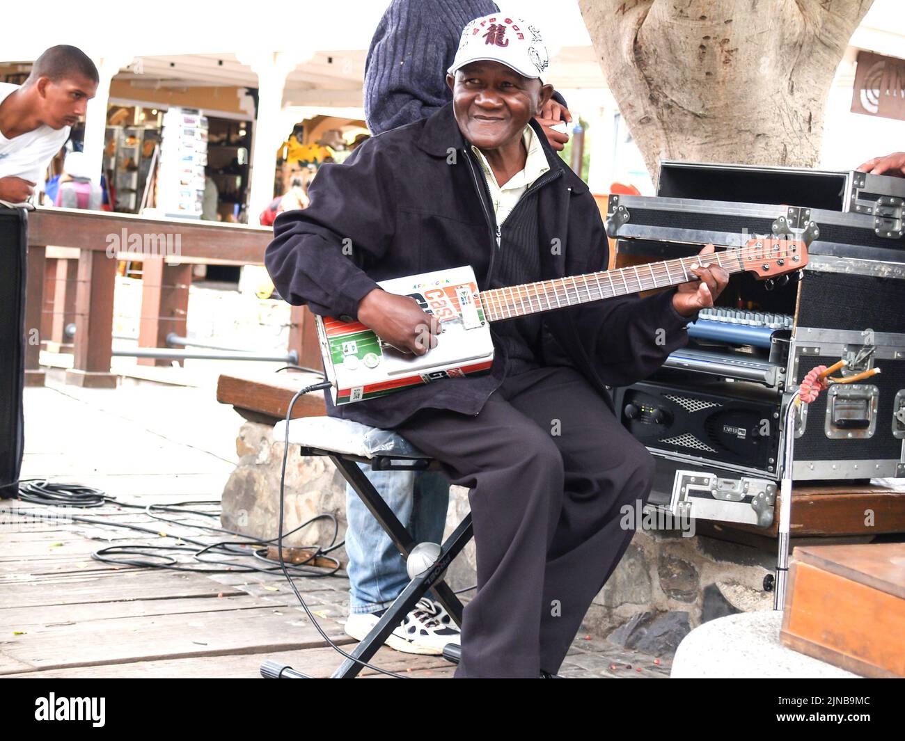 Cape Town South Africa - August 26 2007: African man sitting in street playing guitar made out of old oil can in city. Stock Photo