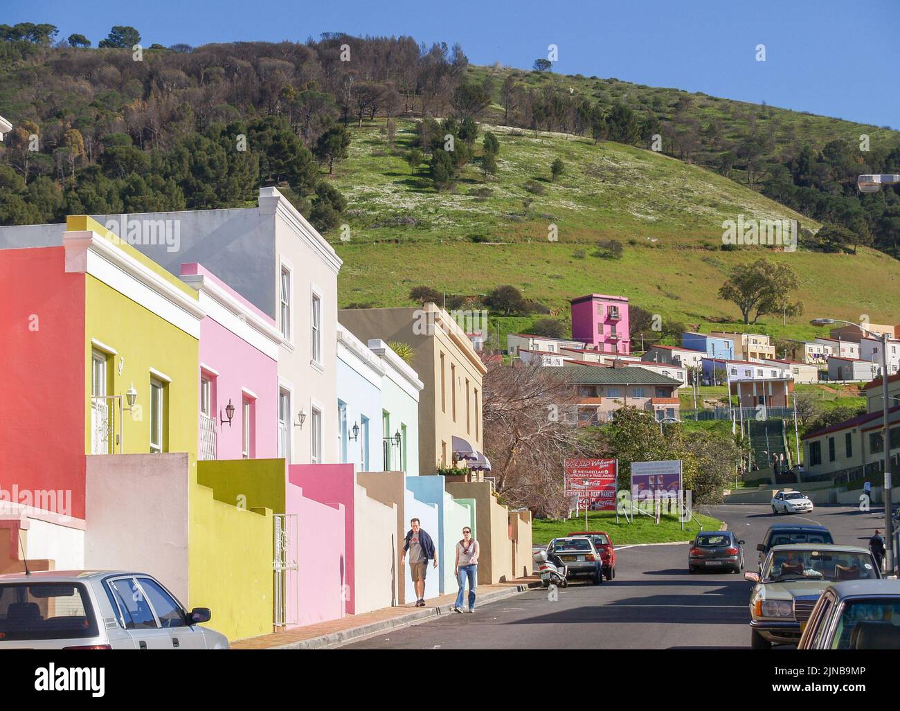Cape Town South Africa - August 28 2007; Street of distinctive pastel colored buildings in district of Bo-Kaap below green hill in Cape Town. Stock Photo