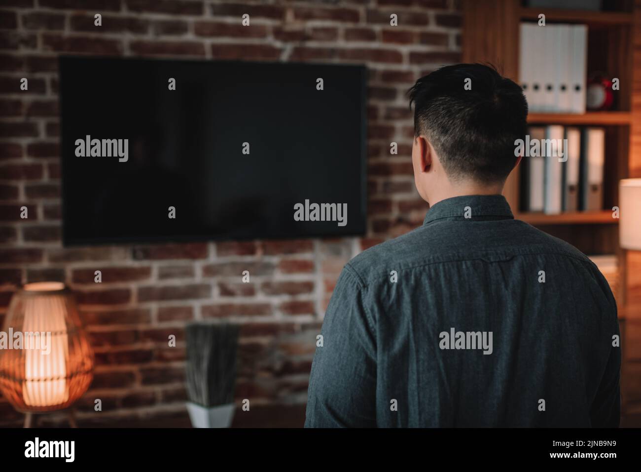 Mature korean man watching tv with empty screen, enjoy show in home