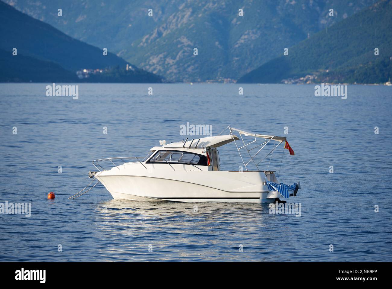 Small yacht with tent roof is moored in sea. Stock Photo