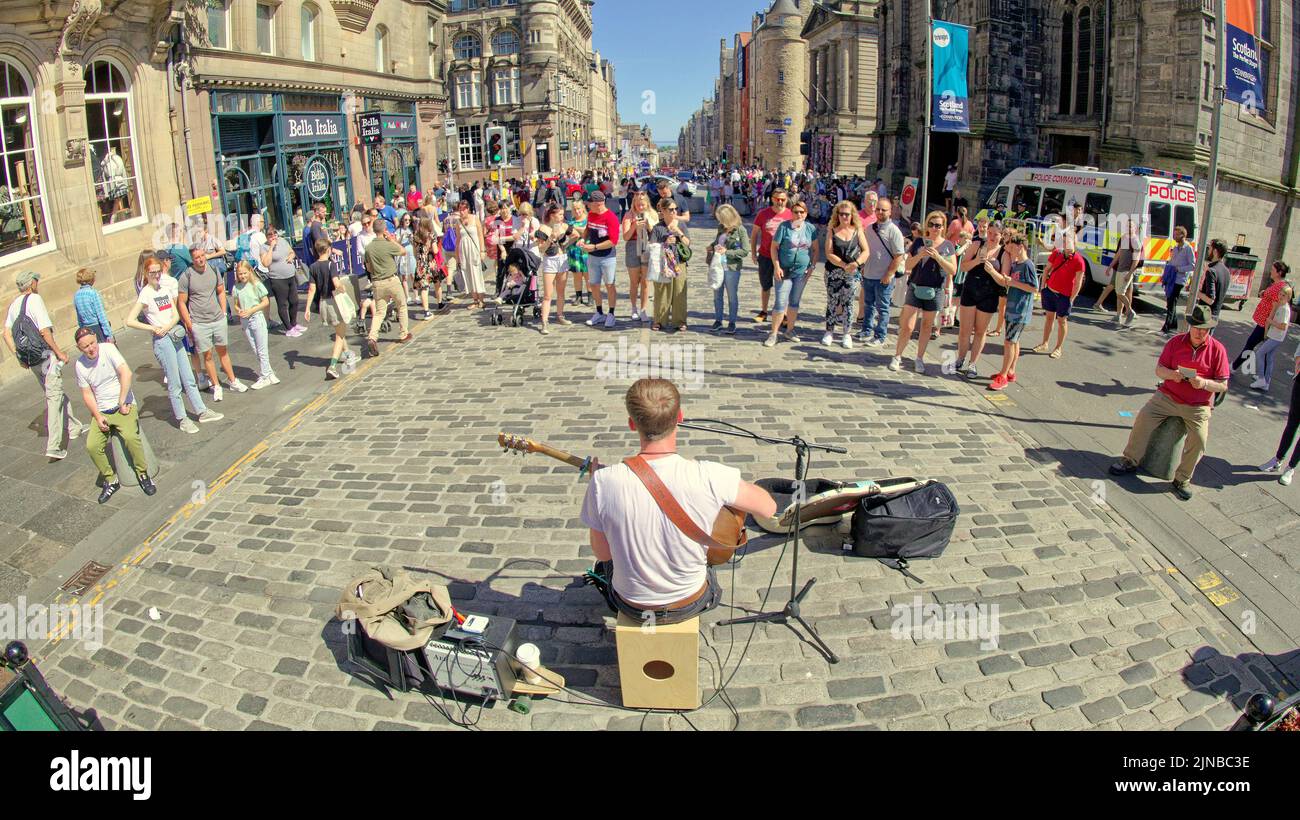 Edinburgh, Scotland, UK  10th August,  2022. UK Weather: The royal mile,  Sunny weather on the way saw locals and tourists toast in the sun as the grass on princes street gardens burned and  they took in the acts and flyer chuckers on the royal mile and mound. Credit Gerard Ferry/Alamy Live News Stock Photo