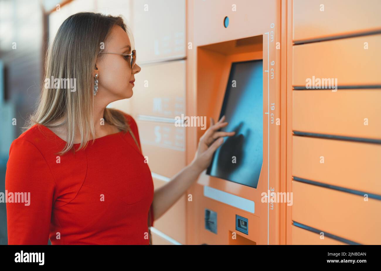 Woman picks up mail from automated self-service post terminal machine ...