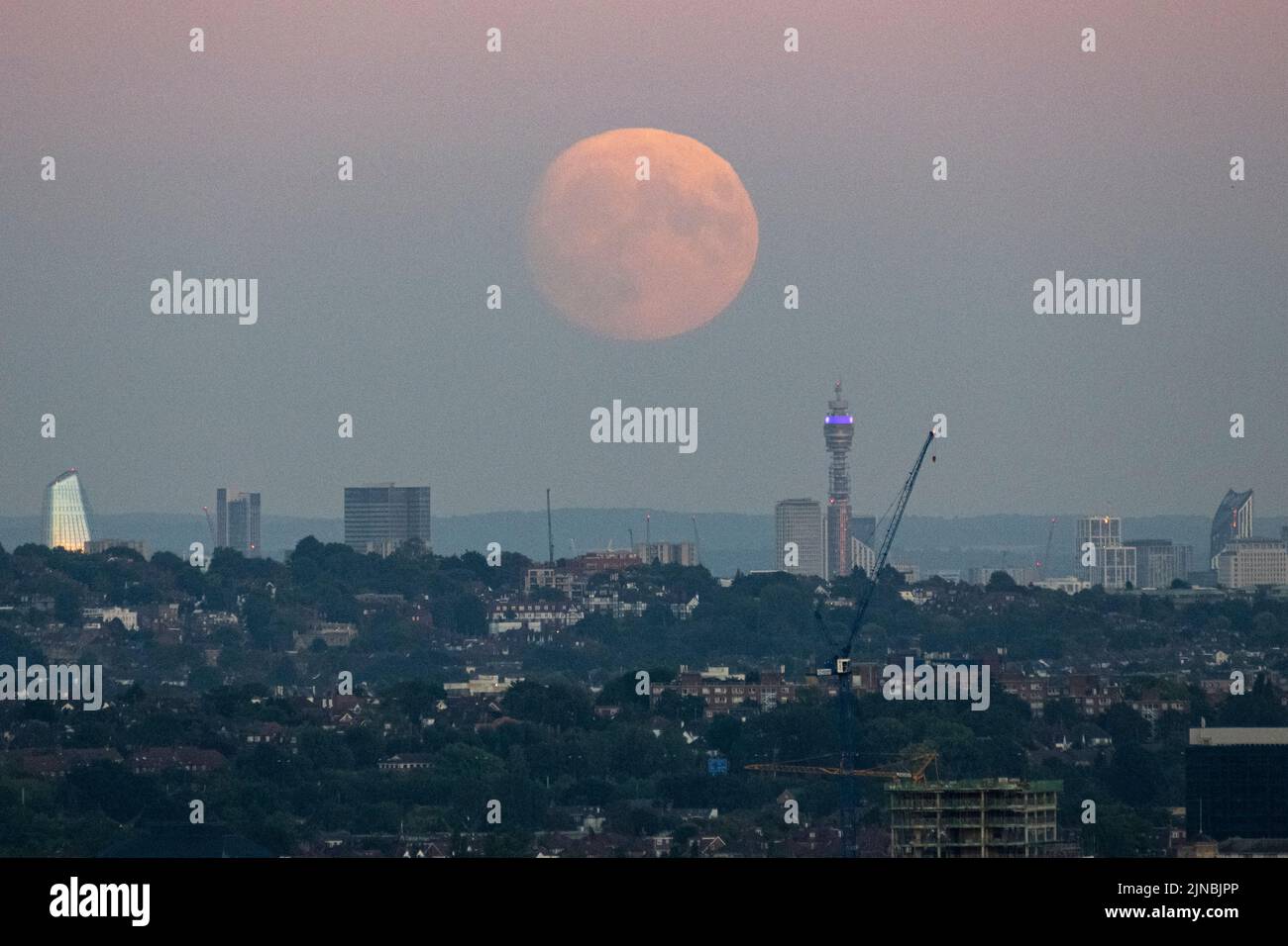 London, UK.  10 August 2022.  UK Weather – A 97.1% waxing gibbous moon rises through a layer of smog over the BT Tower and skyline of the capital.  According to The Old Farmer’s Almanac, August’s full moon (at 02:35 on 12 August) is called the Sturgeon Moon because of the large number of sturgeon fish that were found in the Great Lakes in North America at this time of year.  August’s full moon is also known as a ‘supermoon’ appearing brighter and larger as it will be at its closest point to the Earth in its orbit, known as the perigee. Credit: Stephen Chung / Alamy Live News Stock Photo
