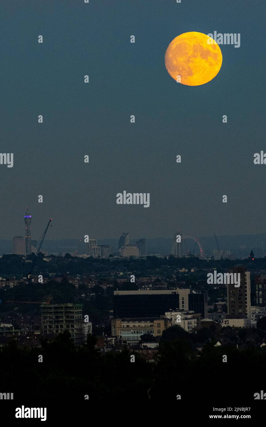 London, UK.  10 August 2022.  UK Weather – A 97.1% waxing gibbous moon rises through a layer of smog over the London Eye and skyline of the capital.  According to The Old Farmer’s Almanac, August’s full moon (at 02:35 on 12 August) is called the Sturgeon Moon because of the large number of sturgeon fish that were found in the Great Lakes in North America at this time of year.  August’s full moon is also known as a ‘supermoon’ appearing brighter and larger as it will be at its closest point to the Earth in its orbit, known as the perigee. Credit: Stephen Chung / Alamy Live News Stock Photo