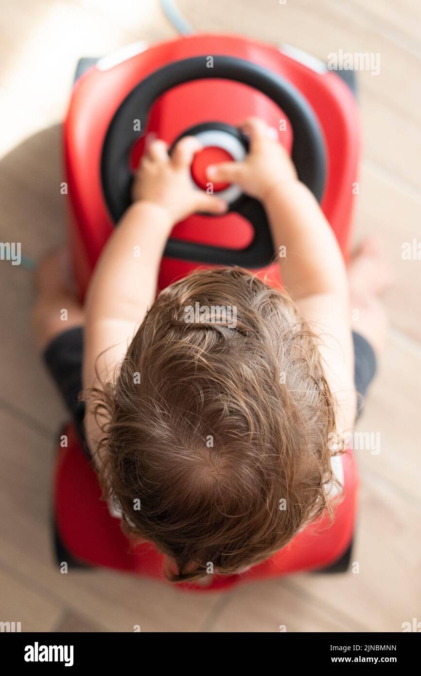 Baby boy, caucasian, one year old, riding a push car. Top view, indoor. Vertical, selective focus. Stock Photo