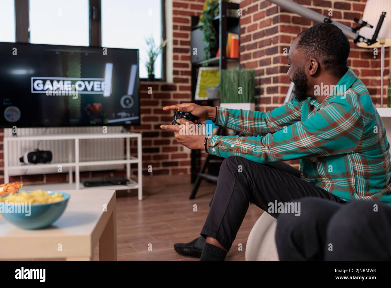 Frustrated african american man playing video games and losing, feeling angry and sad about lost gaming competition. Irritated person using tv console to play game and lose at home party. Stock Photo