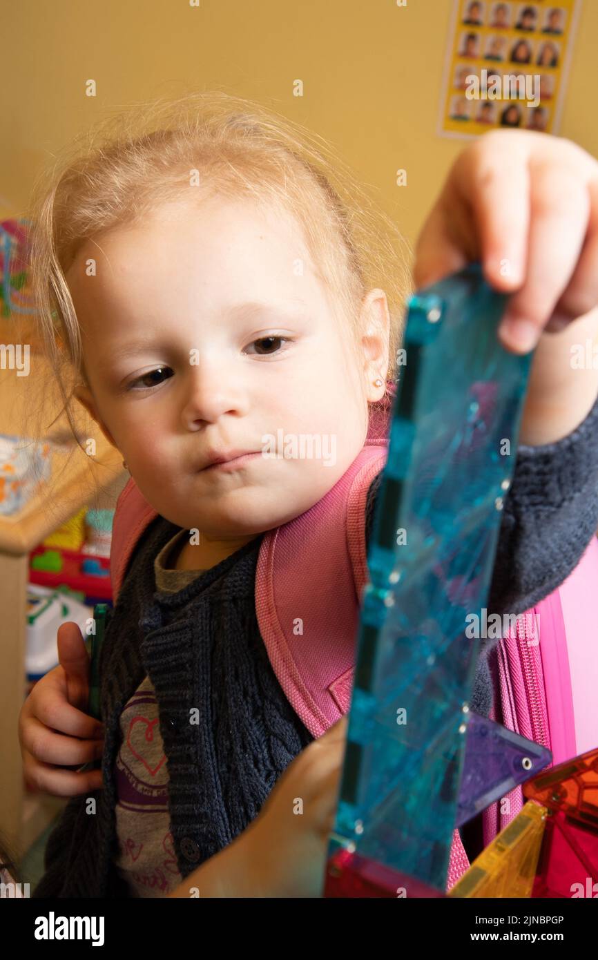 Education Preschool Child Care 2-3 year olds toddler girl making tower out of magnet tiles Stock Photo