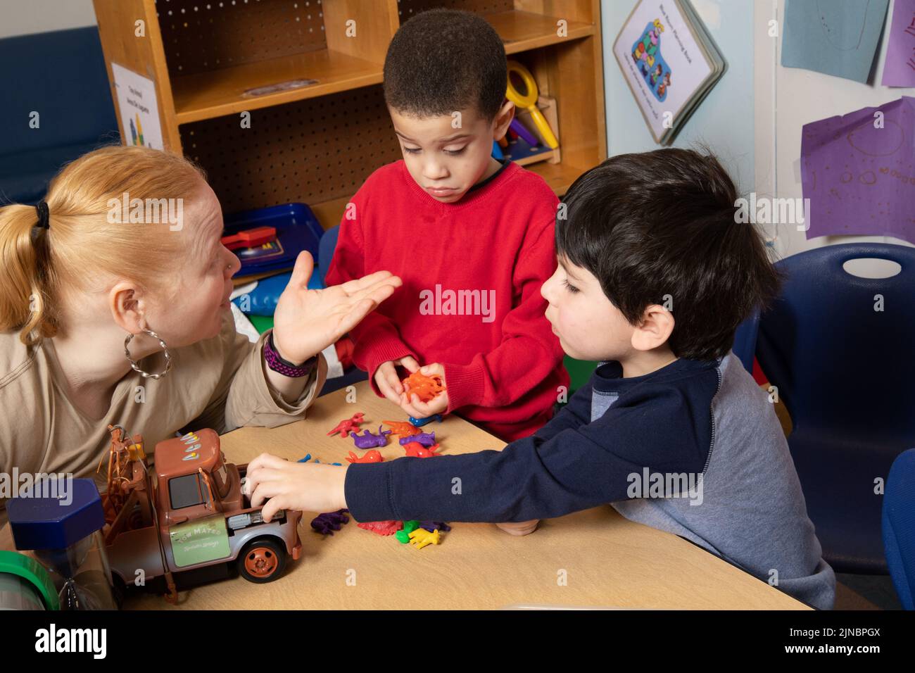 Education Preschool 3 year olds two boys conflict over toy, teacher working with children to resolve conflict, teacher restates problem #3 in series Stock Photo