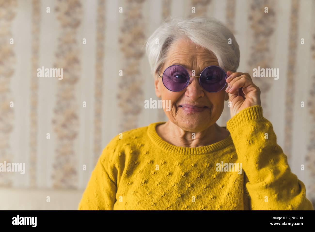 Funny caucasian senior woman, wearing stylish sunglasses and smiling at