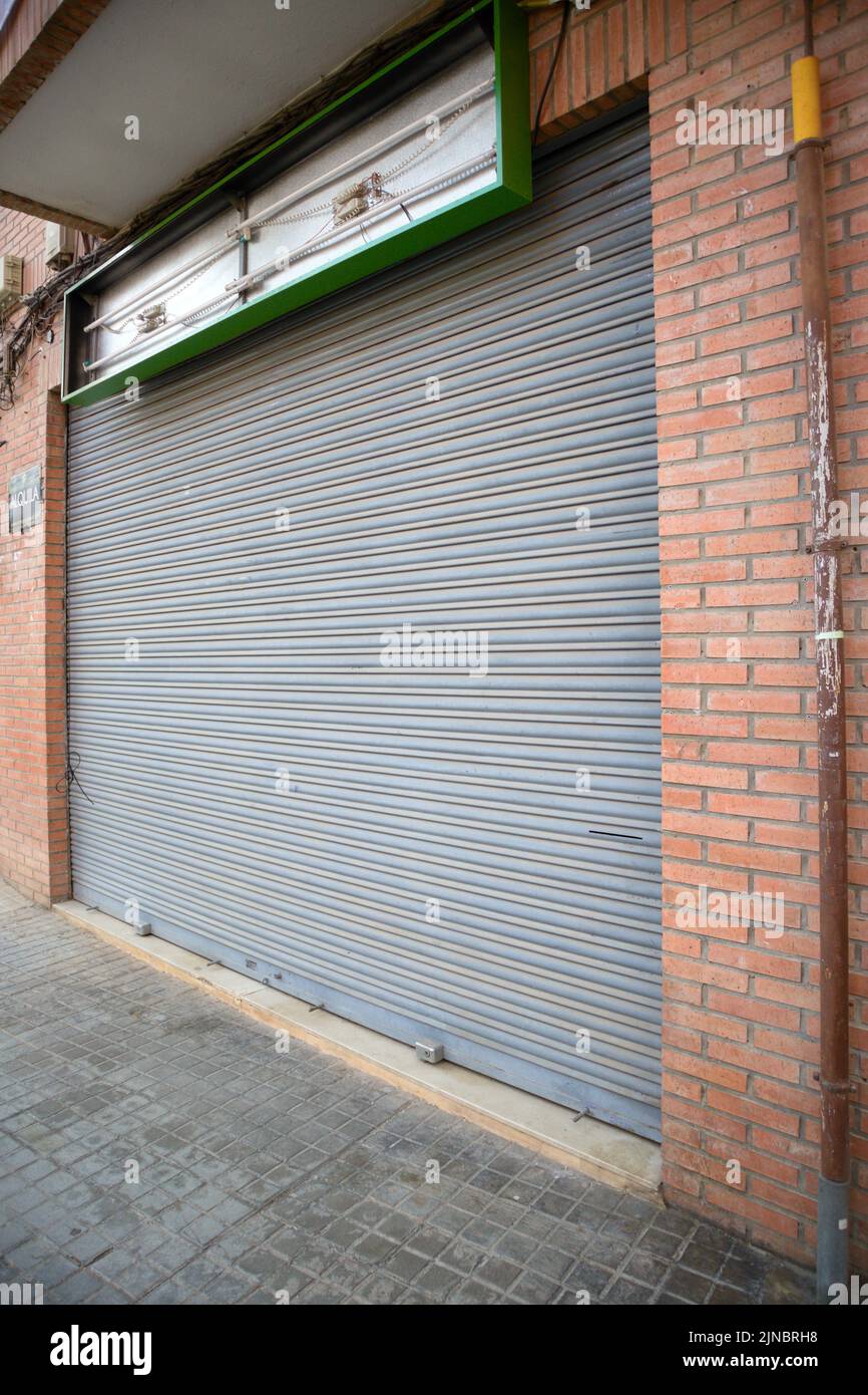 Image of a commercial premises that has closed, has removed the light and has the blind permanently lowered Stock Photo