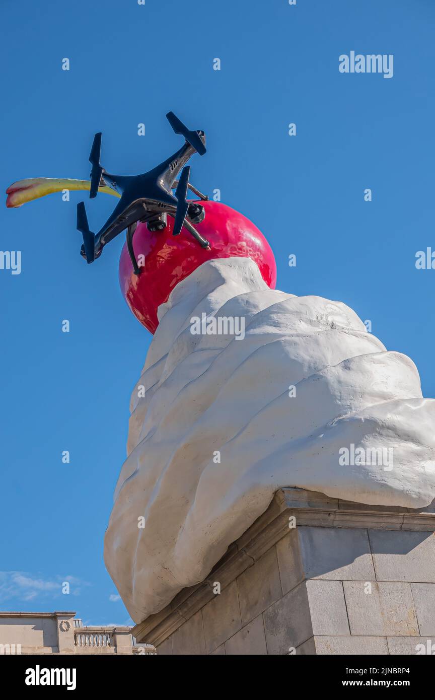 London, UK- July 4, 2022: Trafalgar Square. Closeup of Whipped Cream With red Cherry on top statue, named The End, against blue sky. Drone part of sta Stock Photo
