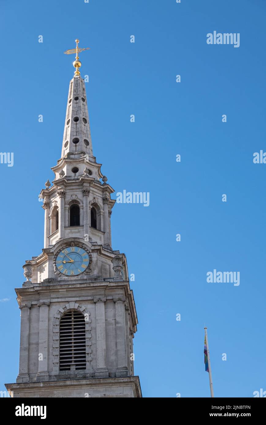 London, UK- July 4, 2022: Trafalgar Square. Spire of Saint Martin-in-the-fields church features clock, against blue morning sky with flag on pole. Stock Photo