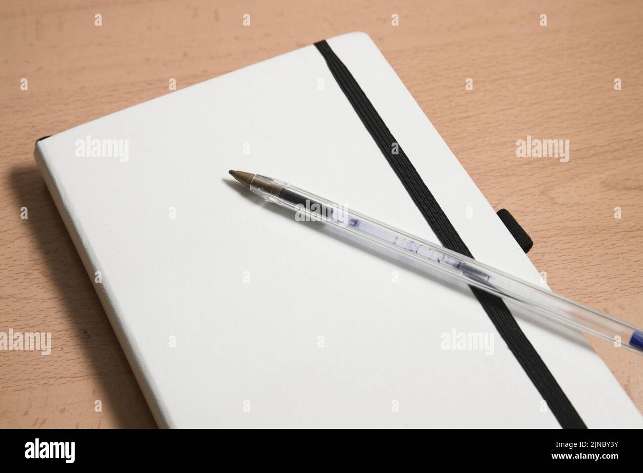 Detail of a white notebook to make notes next to a pen used to make notes. Image with copy space Stock Photo