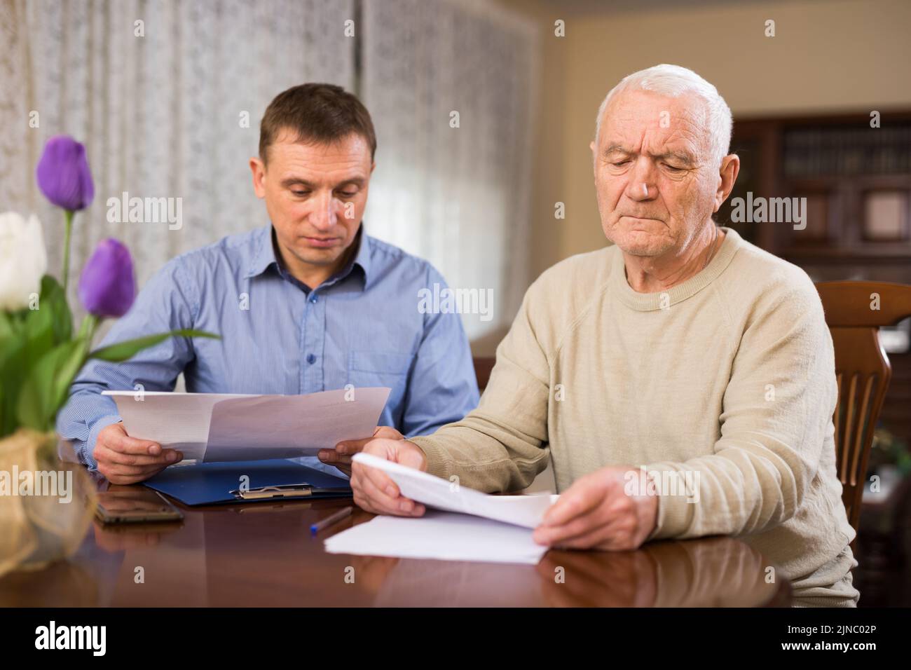 Elderly man and sales manager signing contract of purchase at home ...