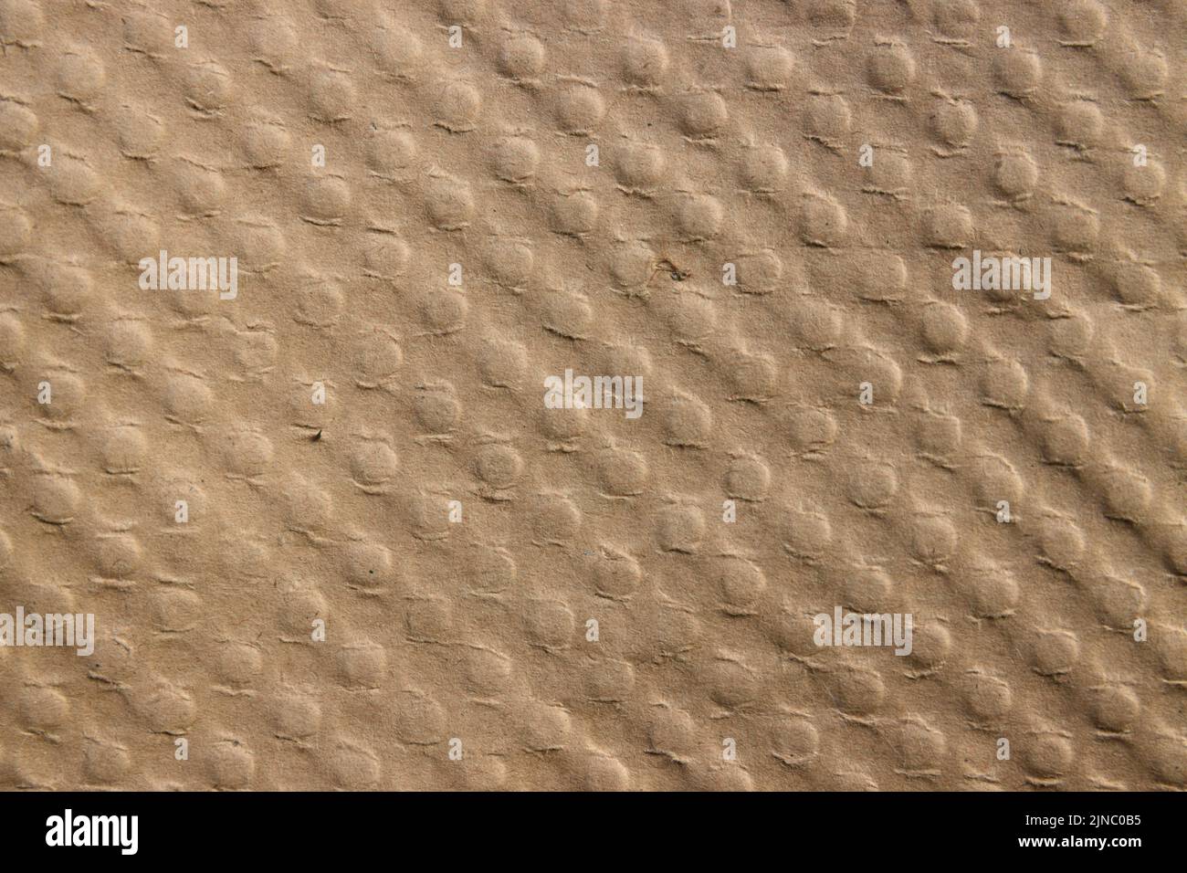 Close-up of a surface of a brown colored cardboard that has a pattern of diagonally aligned buttons Stock Photo