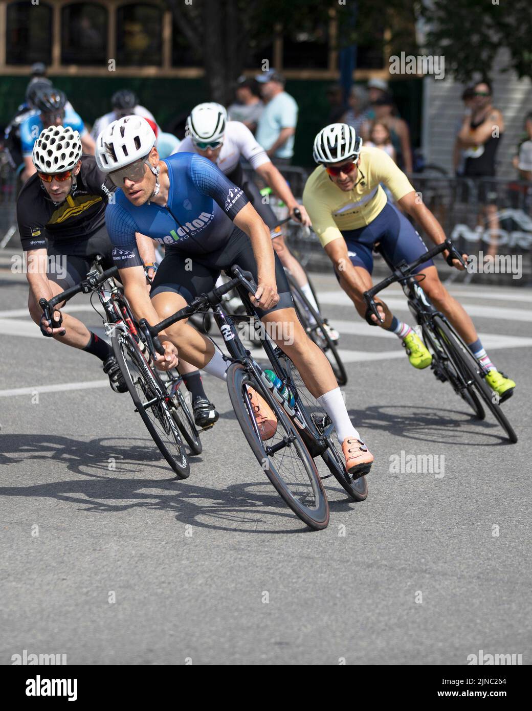 Bicycle racers in the peloton round a corner in the Criterium, a fast bike race where the cyclists ride on a circuit of city streets, Calgary, Canada Stock Photo
