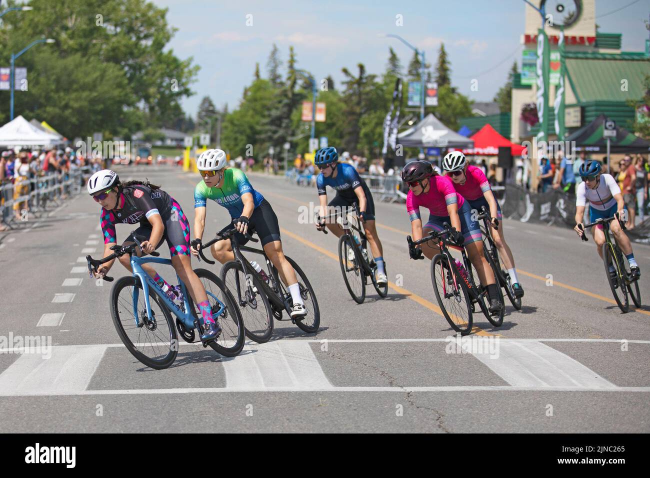 Female cyclists riding a lap of the Criterium, a fast cycling race where the women ride their bicycles on a circuit of city streets in Calgary, Canada Stock Photo