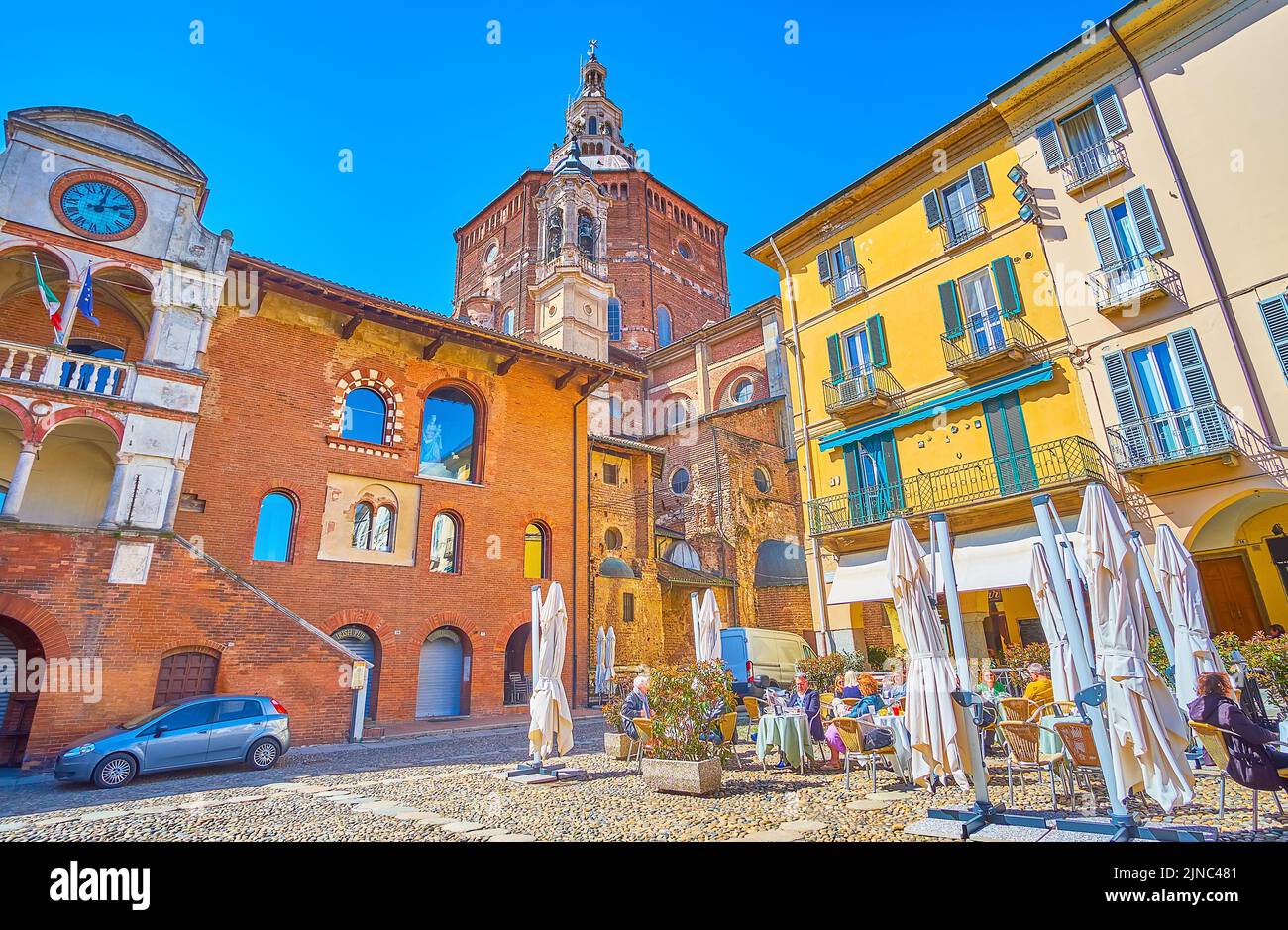 PAVIA, ITALY - APRIL 9, 2022: The view on medieval brick Palazzo Broletto and high dome of Cathedral on background, on April 9 in Pavia, Italy Stock Photo