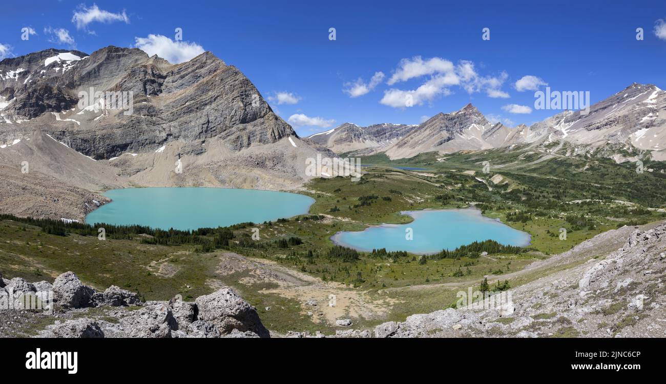 Panoramic Alpine Landscape View with Twin Teal colored Lakes and Rocky Mountain Peaks Skyline. Sunny Day Scenic Summertime Hiking Banff National Park Stock Photo