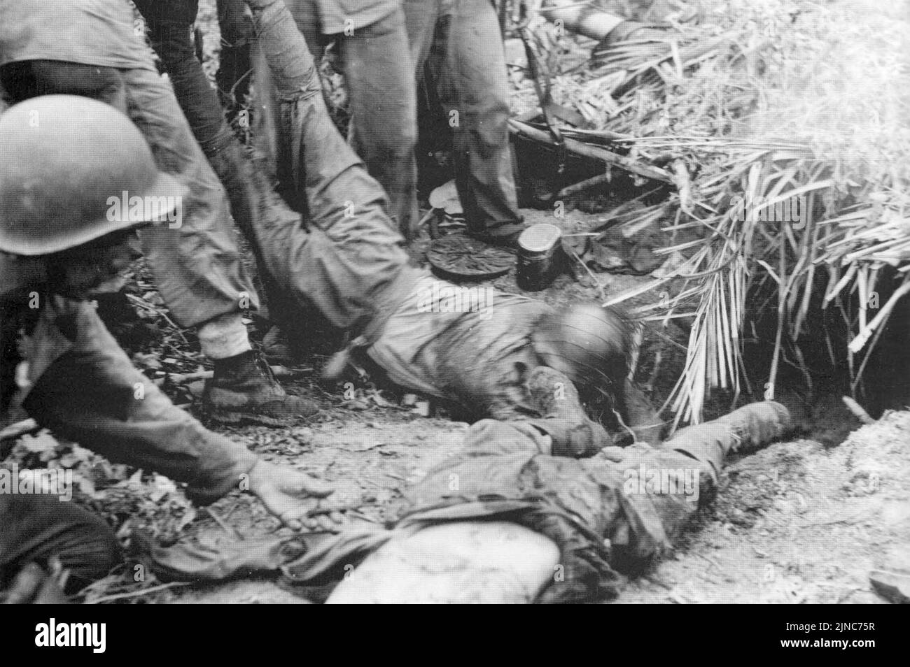 U.S. Marines drag the corpses of Japanese soldiers from their bunker in the Point Cruz area after the battle in early November during the Matinakau Offensive, which was a battle in the Guadalcanal Campaign. Stock Photo