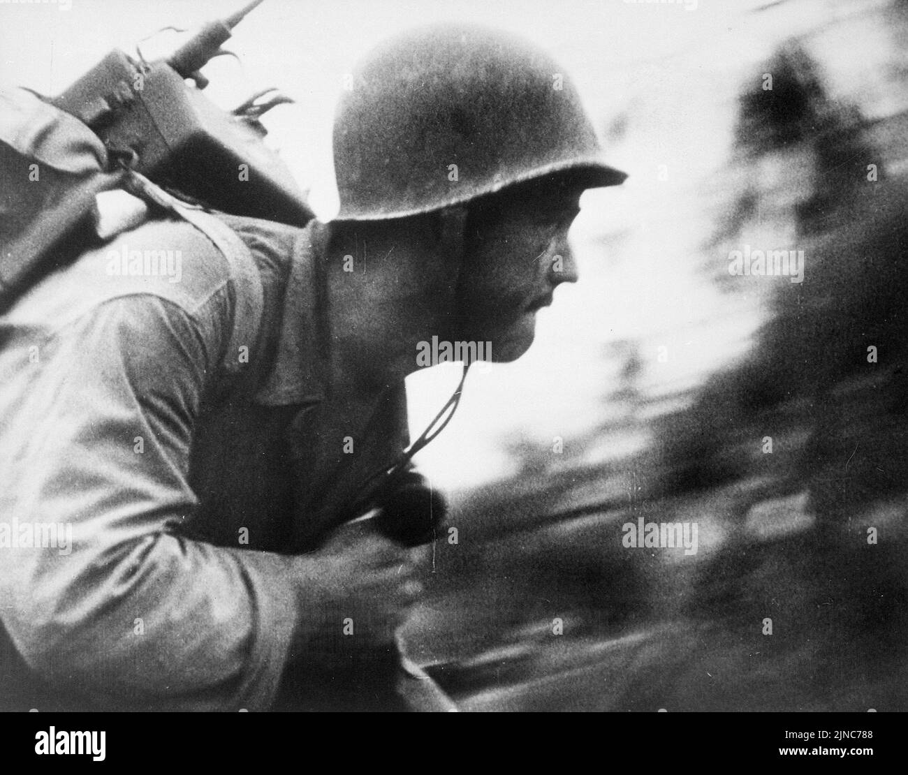 A US Marine charges across the beach on Peleliu Island, Palau Islands, the 'walkie talkie' firmly strapped to his back and clutching a radio phone in his right hand. Stock Photo