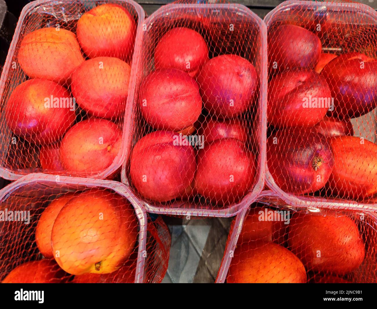 Delicious nectarines are in a cardboard tray on a supermarket shelf and are ready to be sold Stock Photo