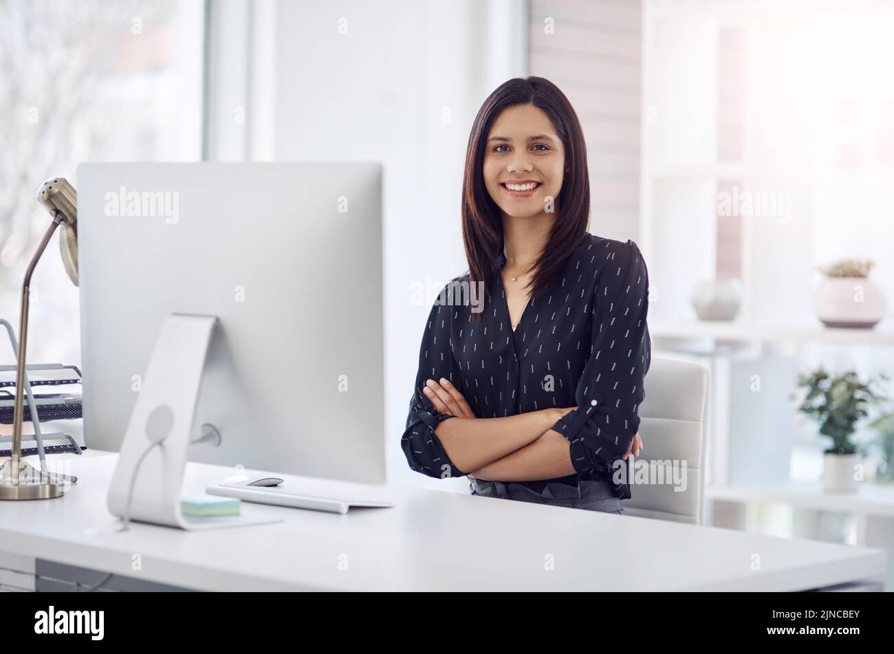 Shes a success story in the making. Portrait of an attractive young businesswoman posing with her arms folded in her office desk at work. Stock Photo