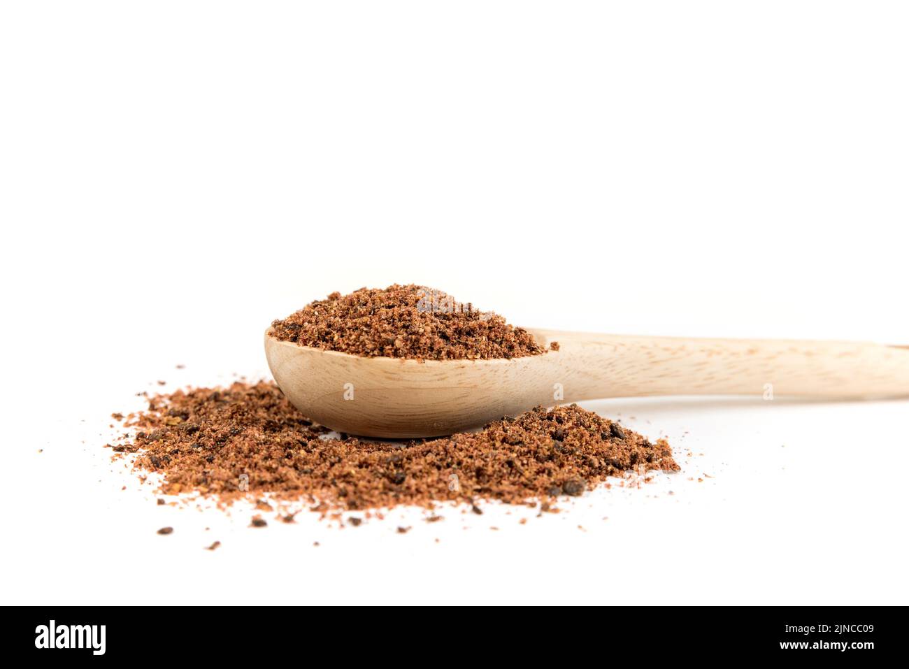 Ground dried sumac berry powder in a wood measuring spoon side view