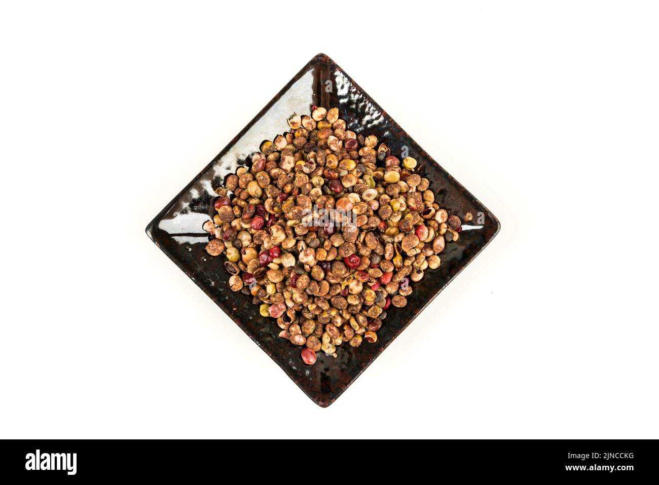 Whole dried sumac berries in a black ceramic plate over white top down