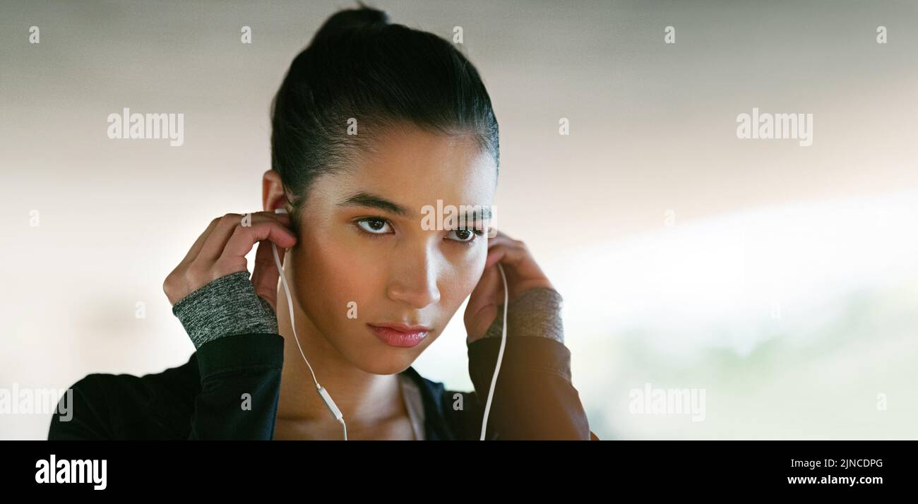 The music is on shes ready to go. an attractive young woman listening to music while working out outdoors. Stock Photo