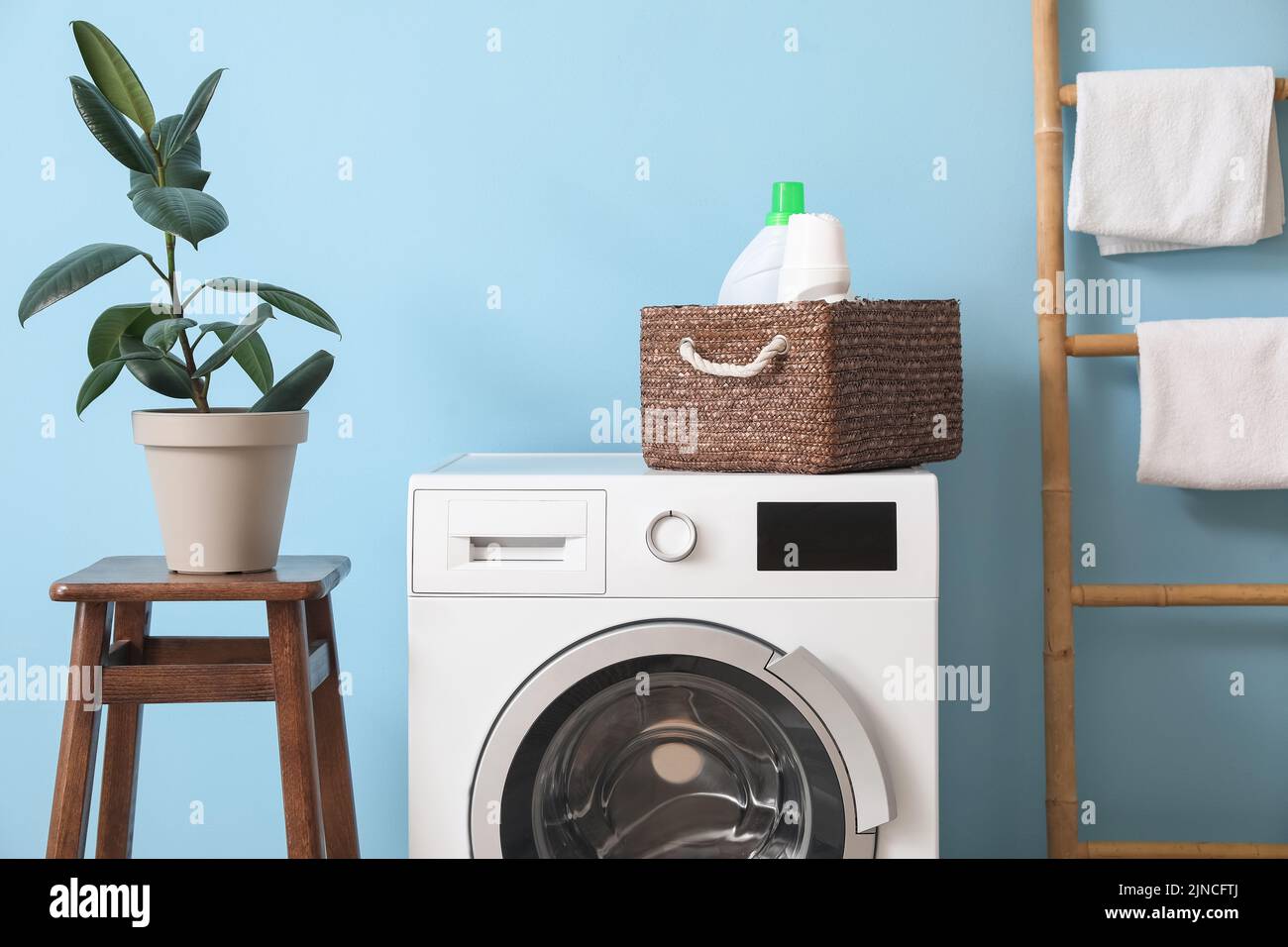 Washing machine with basket and detergent near blue wall in laundry ...