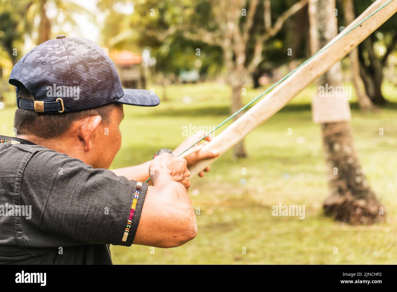 Indigenous older adult aiming at a target with his bow and arrow in the northern caribbean of Nicaragua, central america Stock Photo