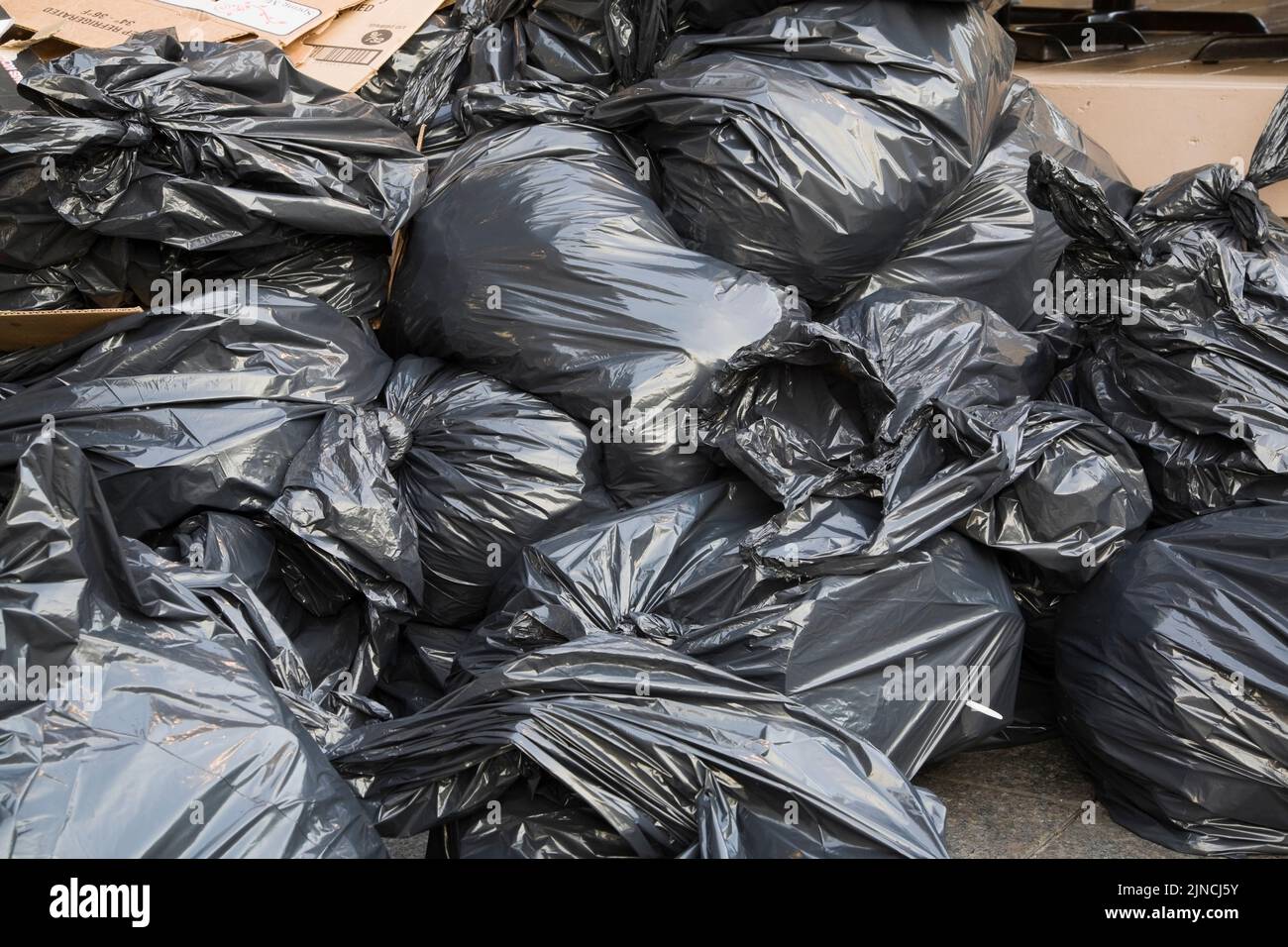 Black plastic garbage bags and flattened cardboard boxes on city sidewalk, Quebec, Canada Stock Photo