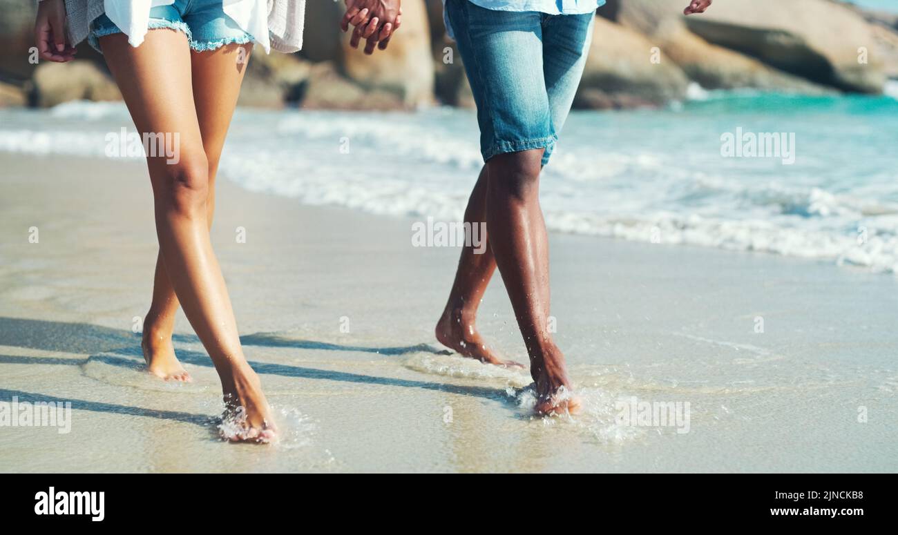 The course of true love is a seashore stroll. an unrecognizable affectionate couple taking a walk at the beach. Stock Photo