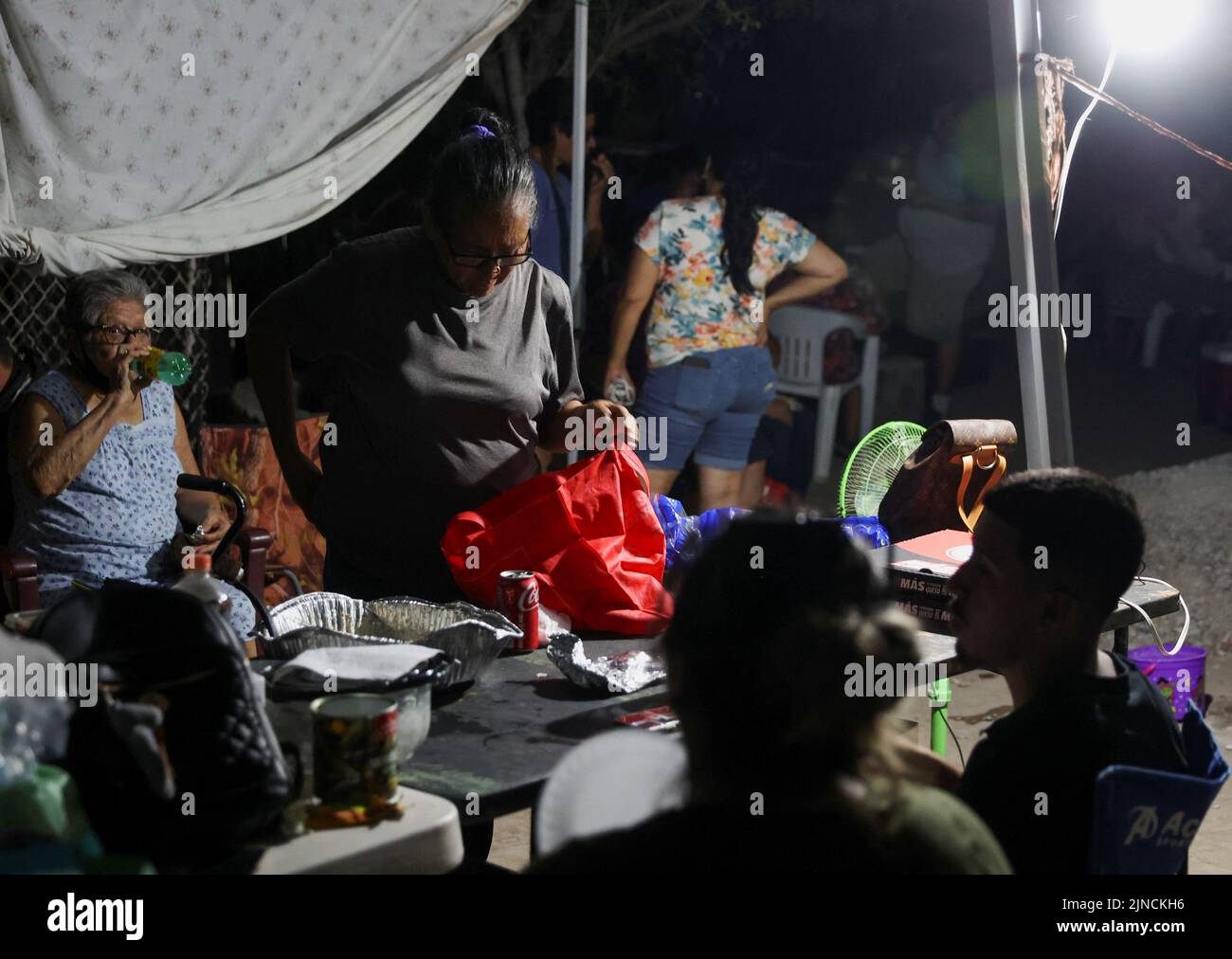 Relatives of miners have dinner and wait for news about their loved ones outside the facilities of a coal mine where a mine shaft collapsed leaving miners trapped, in Sabinas, Coahuila state, Mexico, August 10, 2022. REUTERS/Luis Cortes Stock Photo