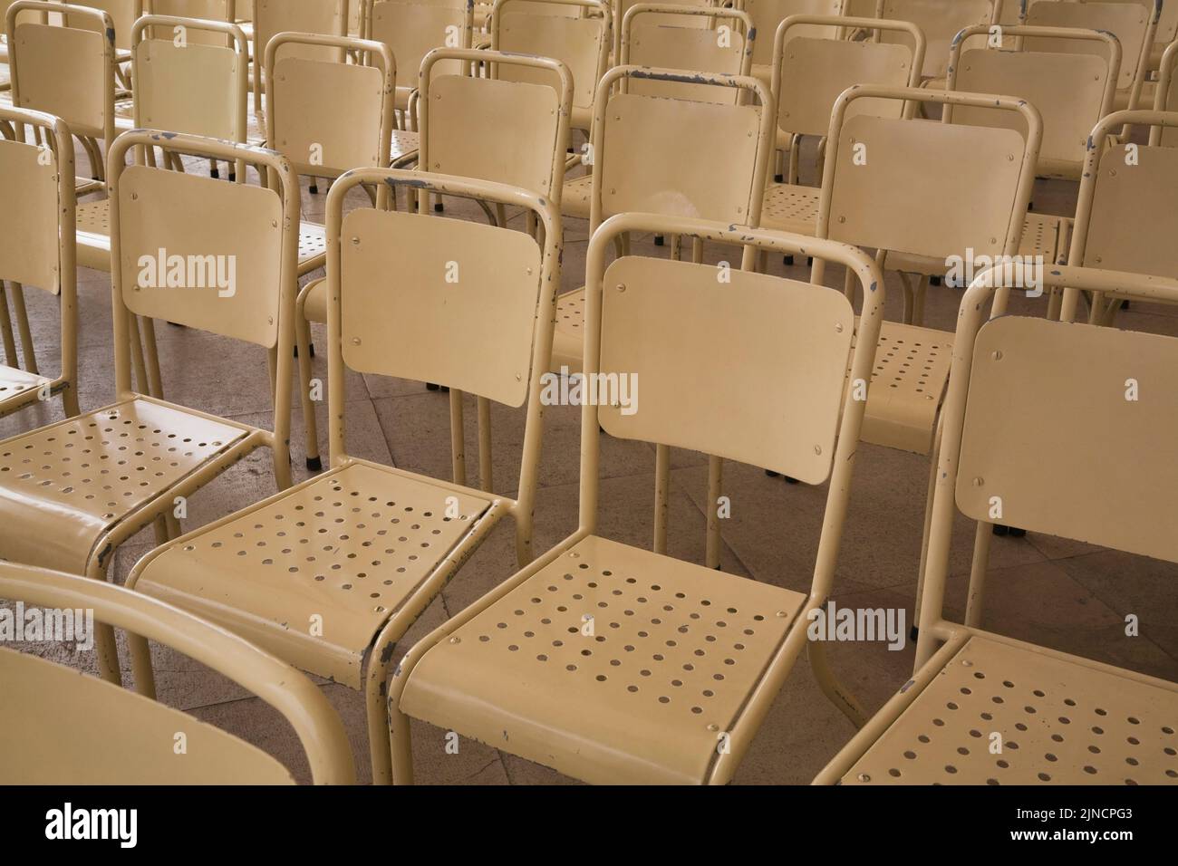 Rows of beige high back metal chairs outdoors, Fatima, Portugal Stock Photo