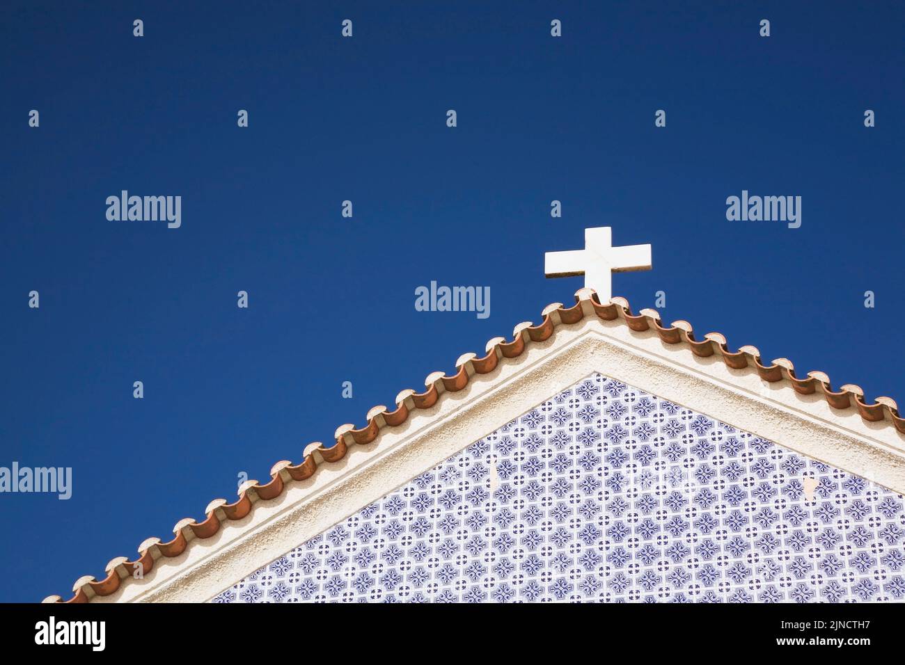 White cross on top of a church roof in Nazare Beach, Portugal. Stock Photo