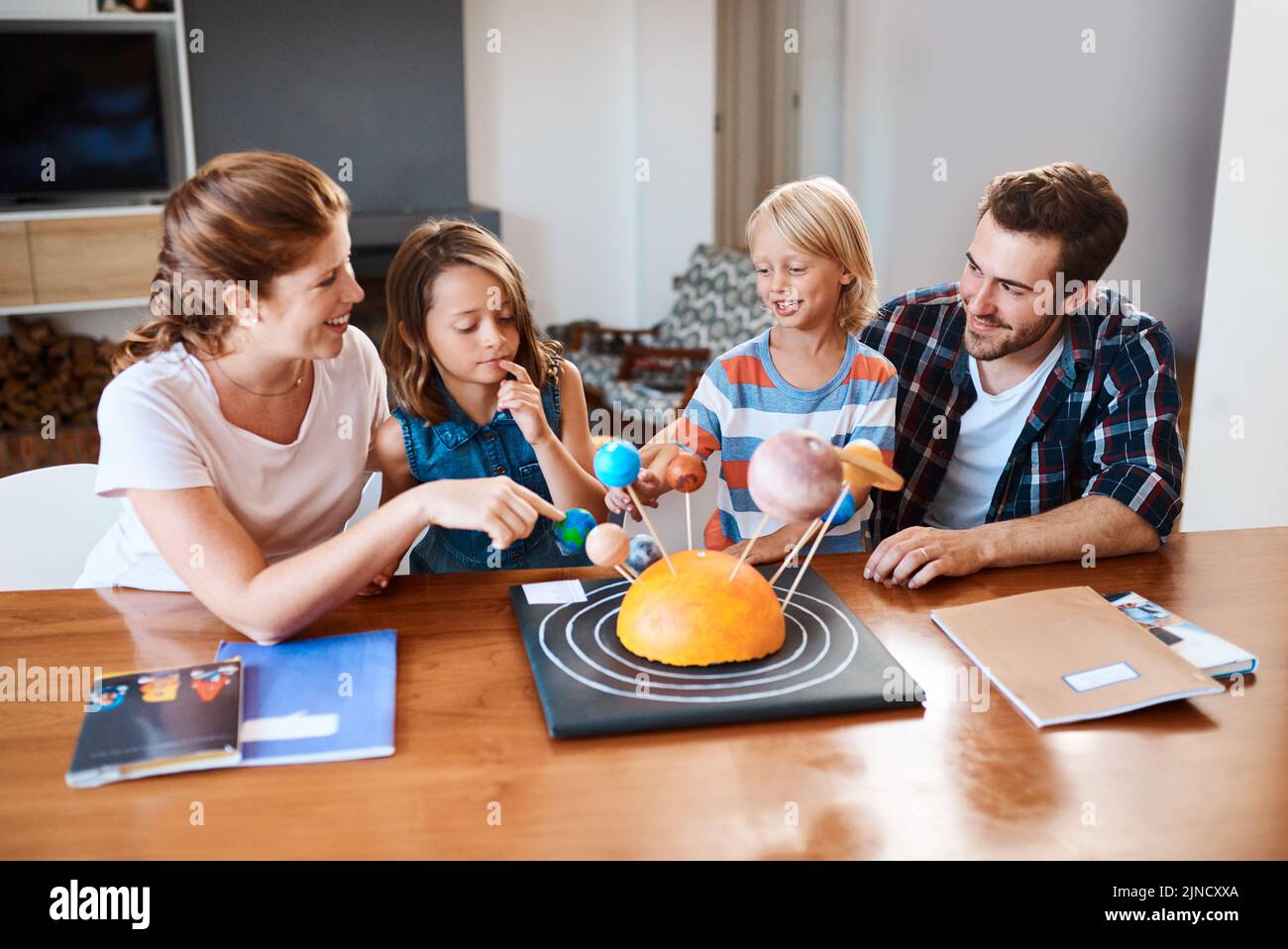 Learning about the universe is always fun. a beautiful young family working together on a science project at home. Stock Photo