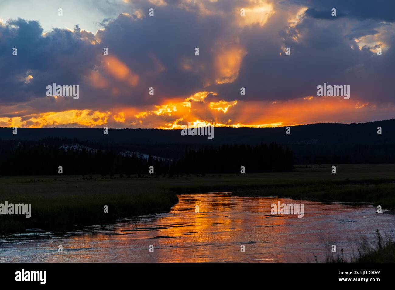 The orange light of the sunset reflects on the Gibbon River east of the Madison Junction area of Yellowstone National Park, Teton County, Wyoming, USA Stock Photo