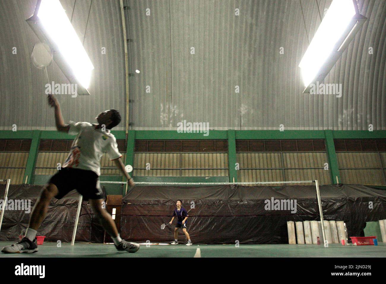 Young badminton athletes playing in a match game for men's singles during a training session at Jaya Raya badminton club in Jakarta, Indonesia. Stock Photo