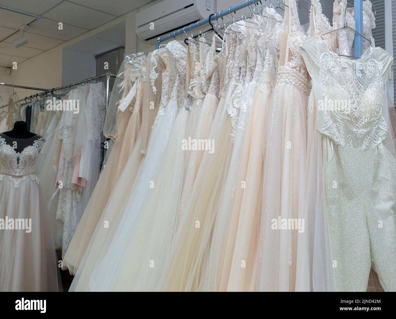 White and cream wedding dresses on a hanger in a bridal boutique. Close up. Stock Photo