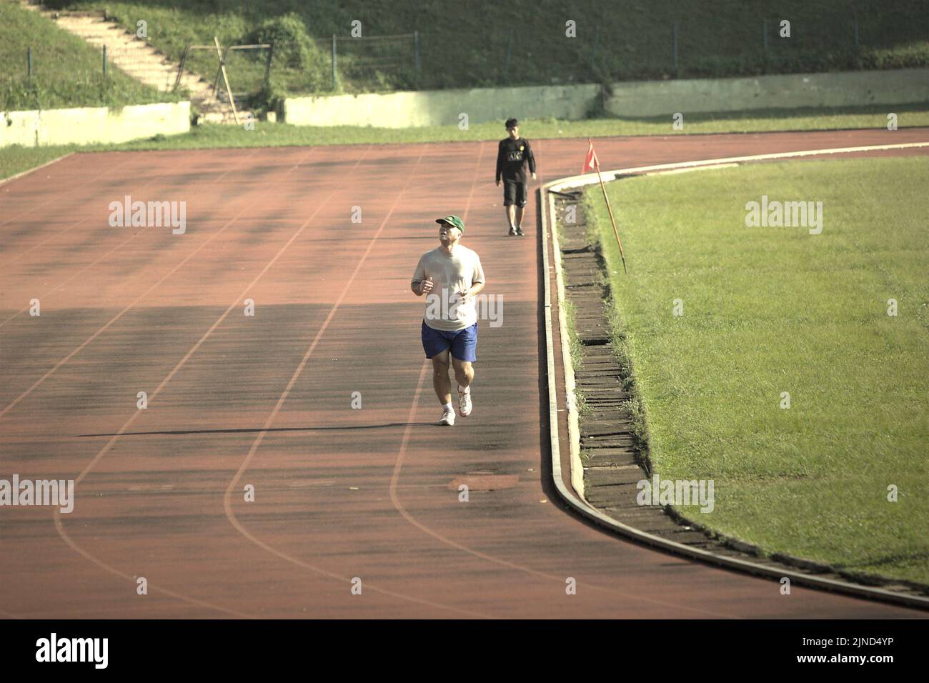 Men jogging on the athletic track of the football field in Ragunan Sports School and Sports Complex in Ragunan, Pasar Minggu, Jakarta, Indonesia. Stock Photo