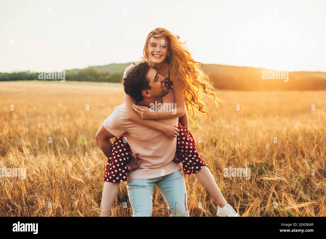 Caucasian man giving the girl a piggy back ride as they smile at the camera while enjoying a day in the country. Harvesting agriculture and plantation Stock Photo