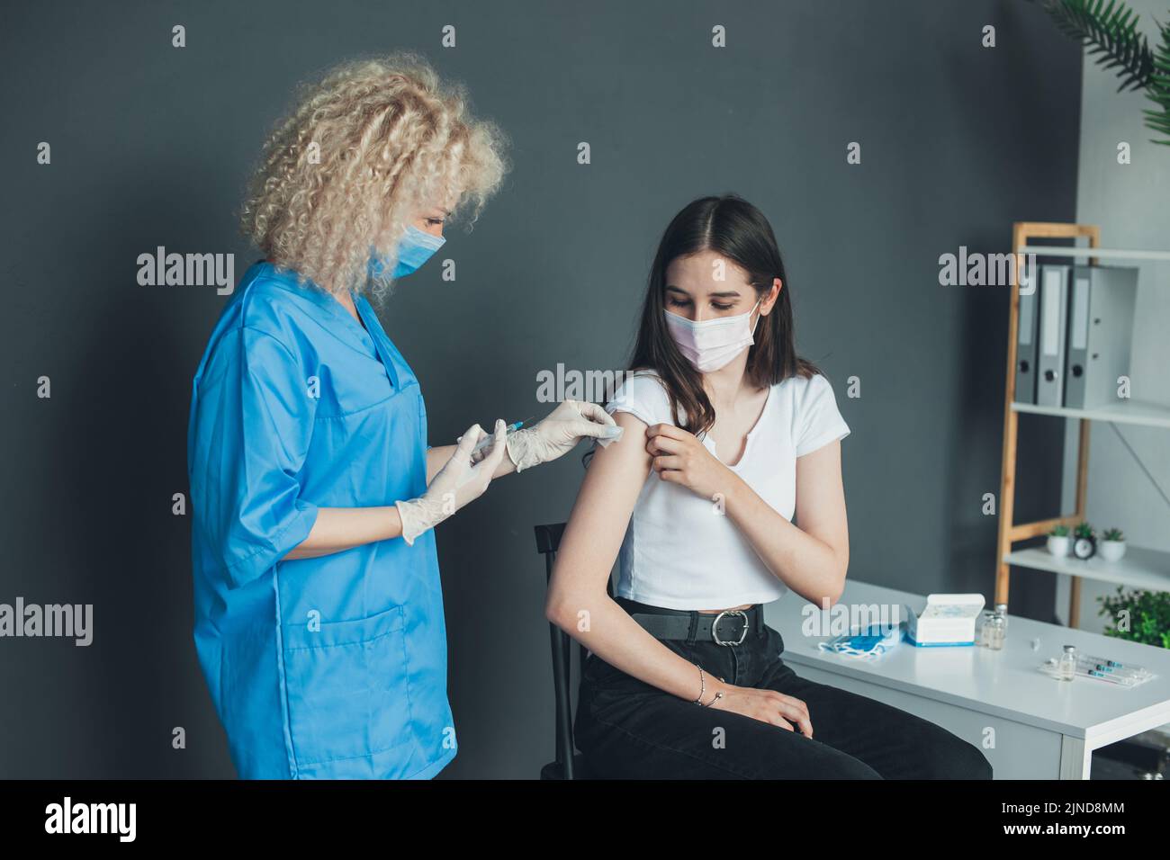 Patient getting vaccinated with covid vaccine intramuscular injection during doctor's appointment in hospital. Vaccine, human clinical trial and Stock Photo
