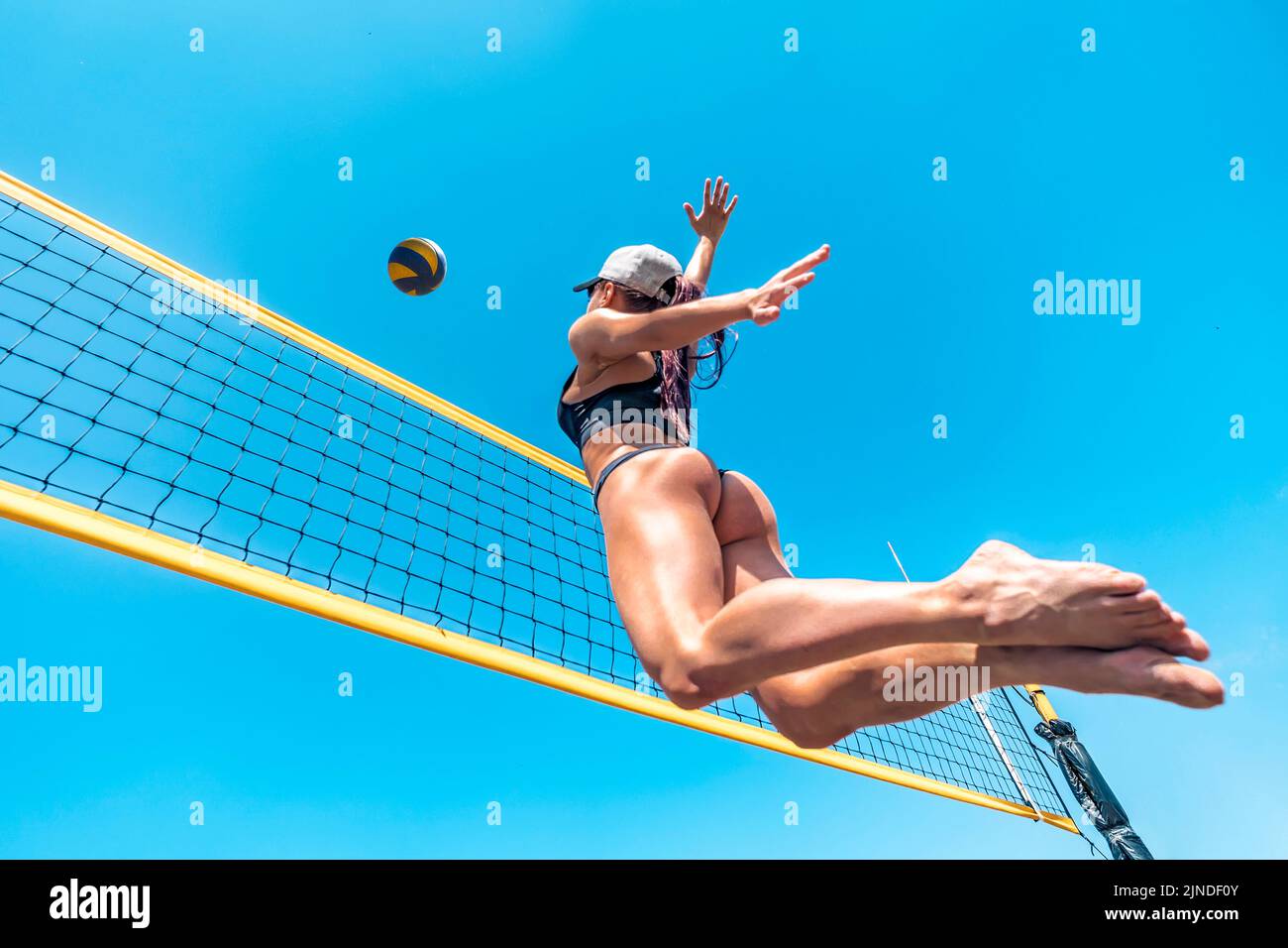 Young woman beach volleyball player. Jump up of sports young woman playing volleyball on sea beach against the blue sky. concept of a healthy lifestyl Stock Photo