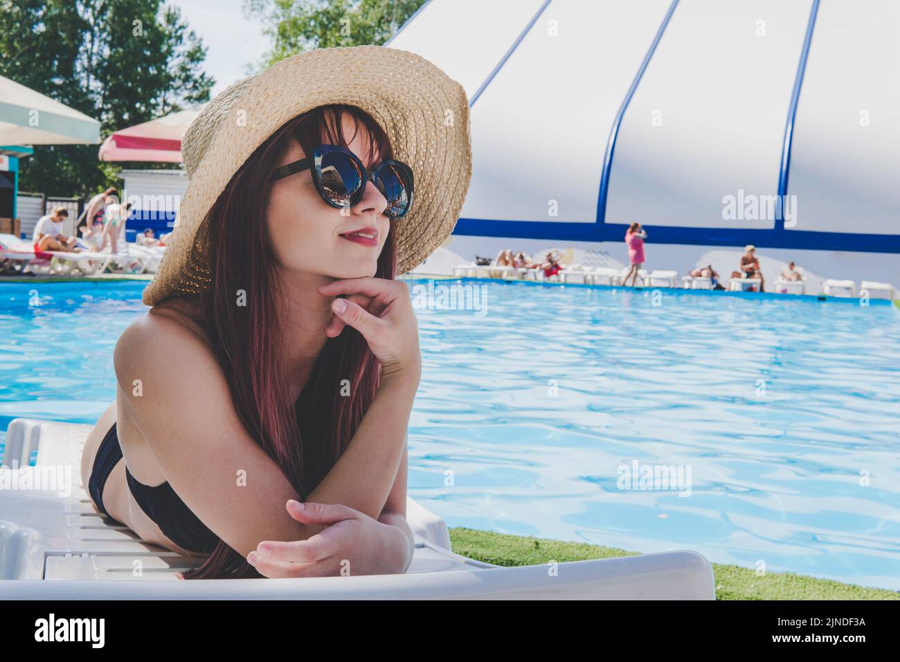 Woman Summer Fashion. Happy Sexy Smiling Girl With Fit Body, Healthy Skin In Bikini, Sun Hat, Sunglasses Sunbathing By Swimming Pool On Travel Holiday Stock Photo