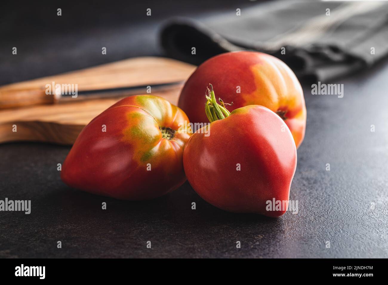 Bull heart tomatoes on a black table. Stock Photo