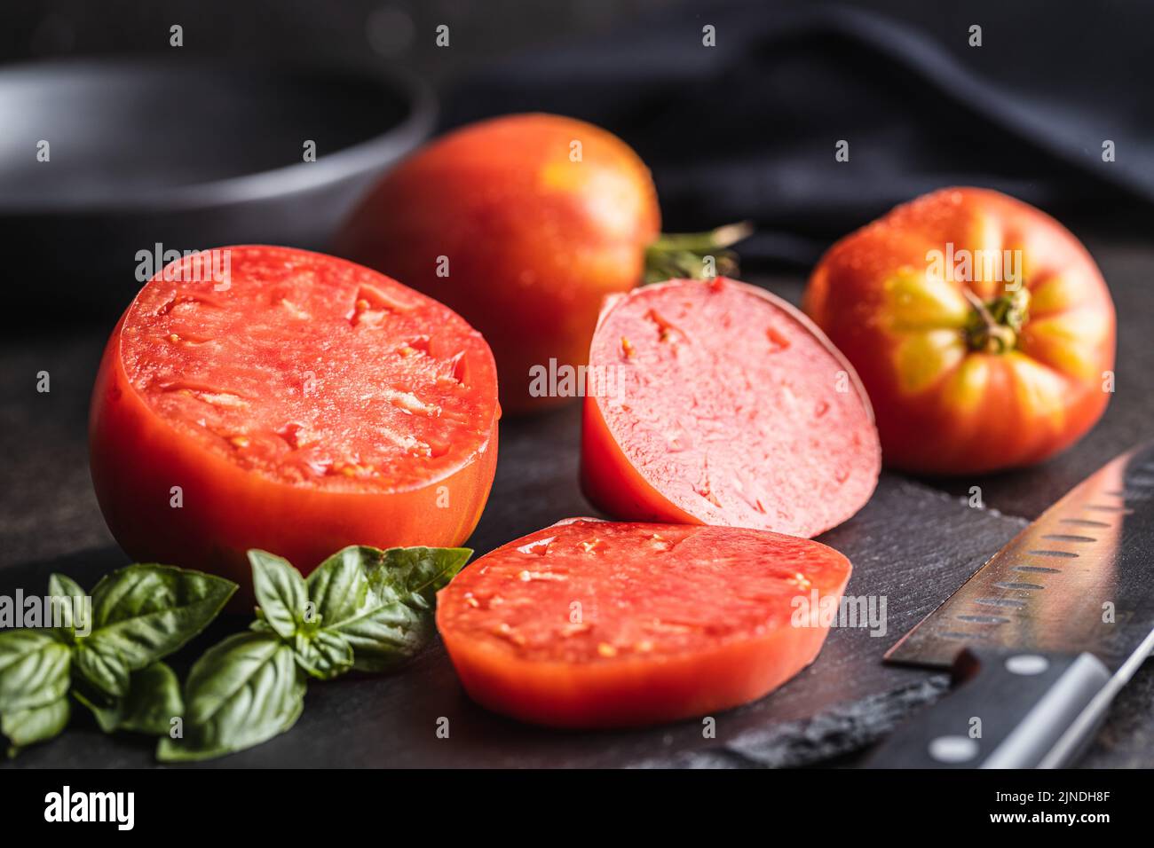 Sliced bull heart tomatoes on a black table. Stock Photo