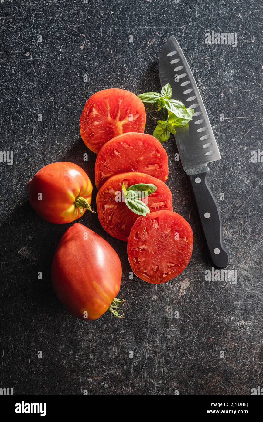 Sliced bull heart tomatoes on a black table. Top view. Stock Photo