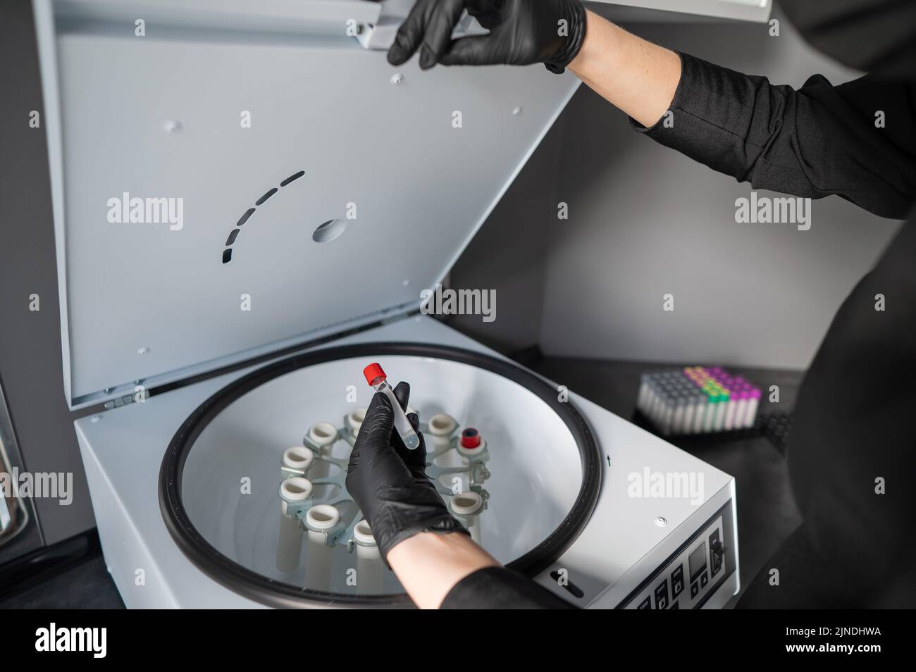 The doctor takes out a test tube with blood plasma from the centrifuge
